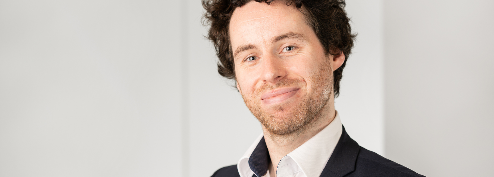 Headshot of a dark curly haired white male.